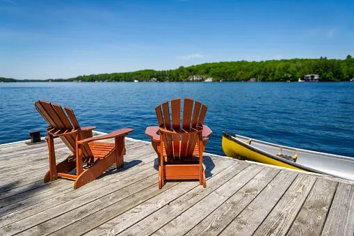 Two Adirondack chairs on a wooden dock looking out across a North Idaho lake.